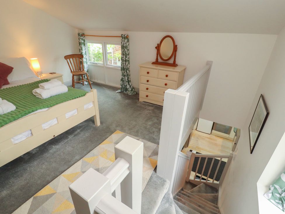 A bedroom with a bed and dresser at Juniper Hayloft in Ambleside
