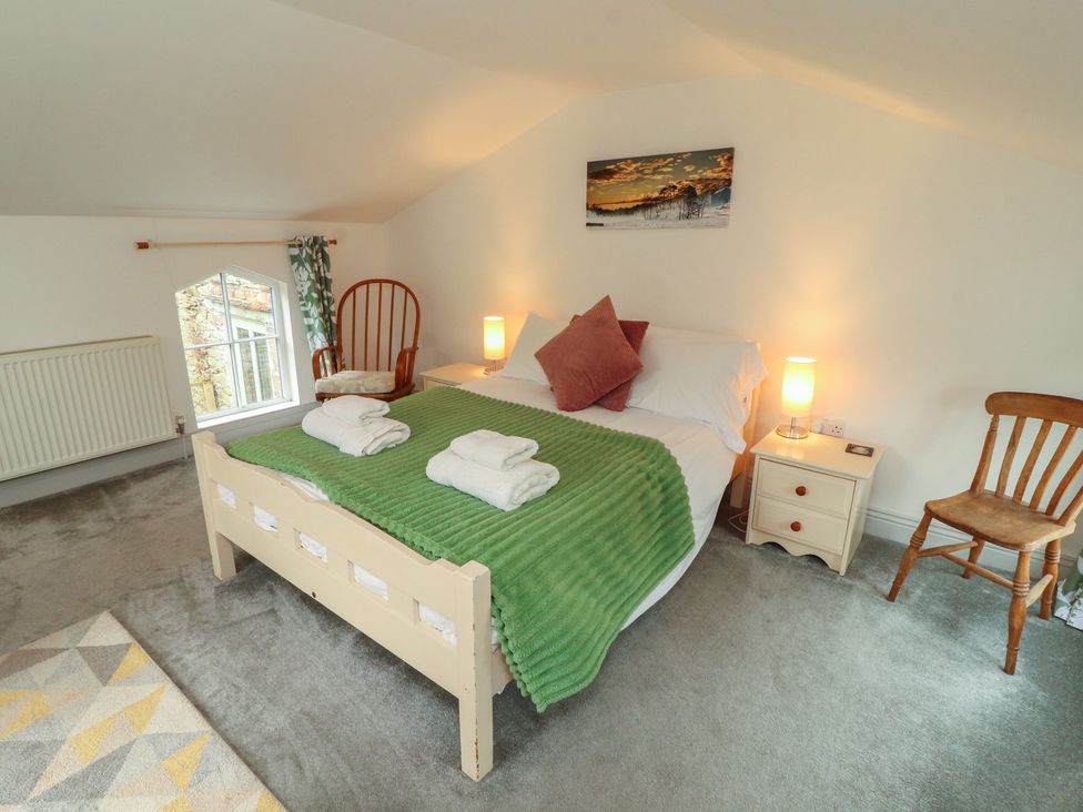A bedroom with a bed, towels, lamp, chair at Juniper Hayloft in Ambleside