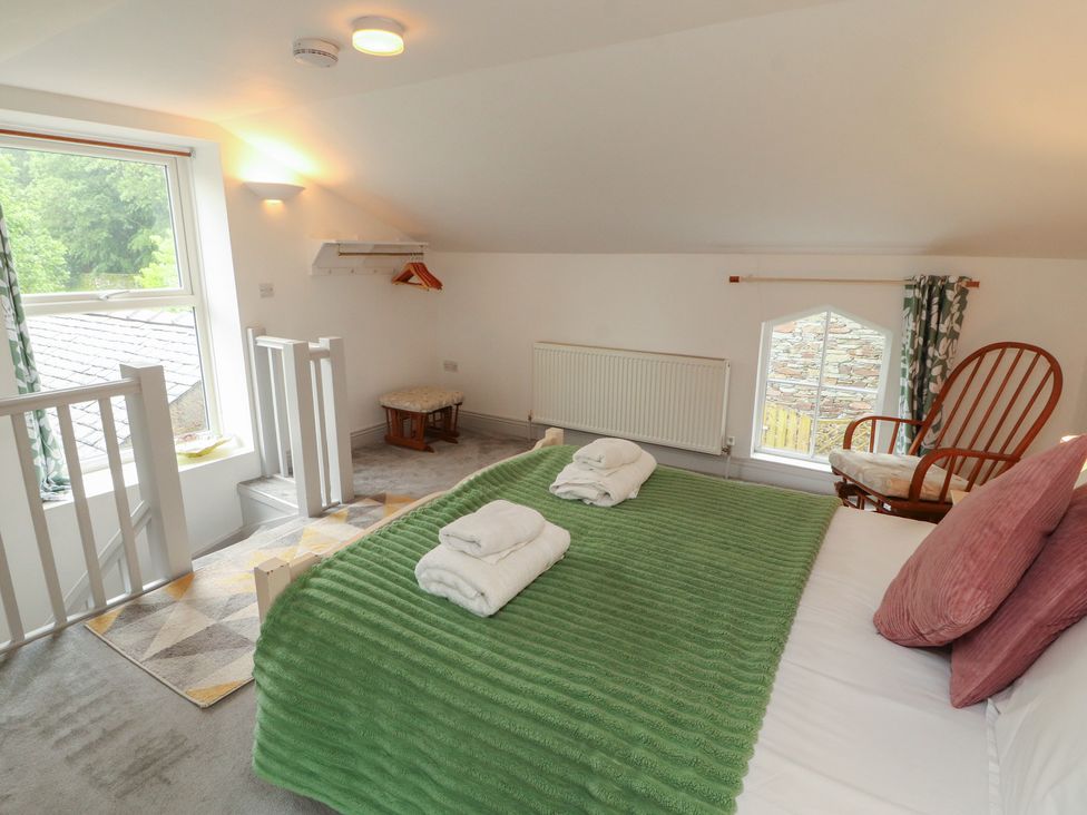 A bedroom with a bed and chair at Juniper Hayloft in Ambleside