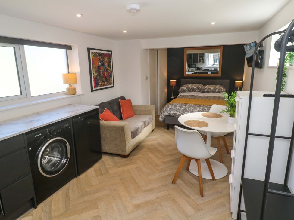 A studio with a washing machine, sofa, dining table, and bed at The Annex in Penzance