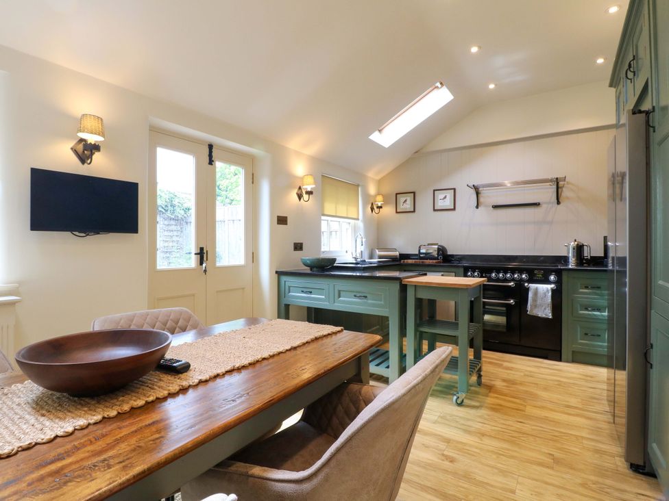 A kitchen with a dining table and stove at Christmas Cottage in Bakewell