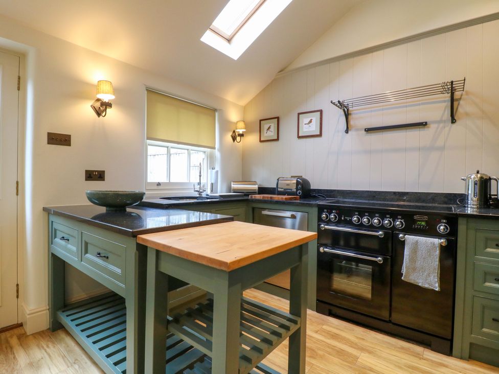 A kitchen with a stove and kitchen island at Christmas Cottage in Bakewell