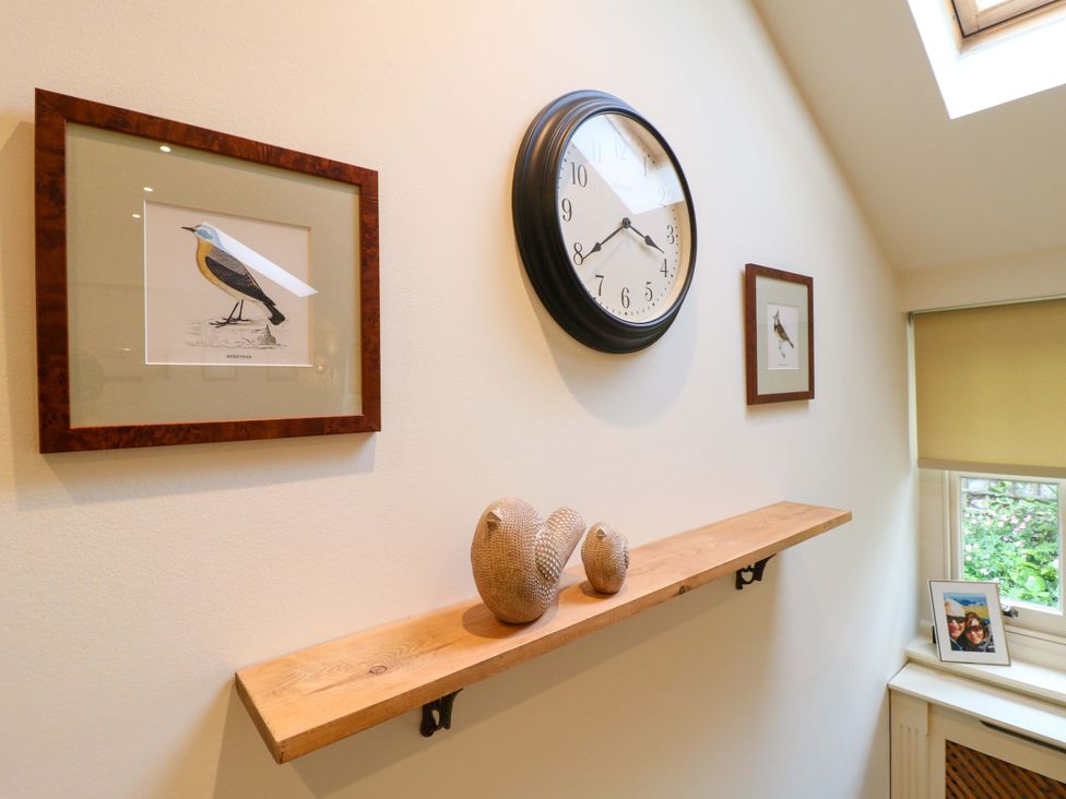 A living room with a clock and framed artwork at Christmas Cottage in Bakewell