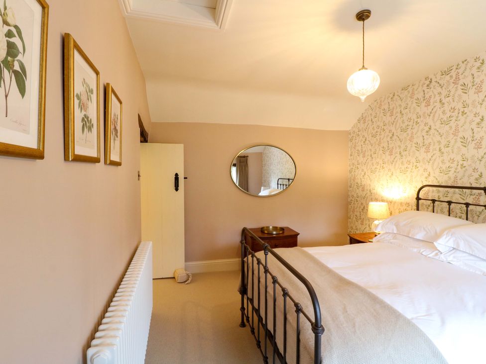 A bedroom with a bed and mirror at Christmas Cottage in Bakewell