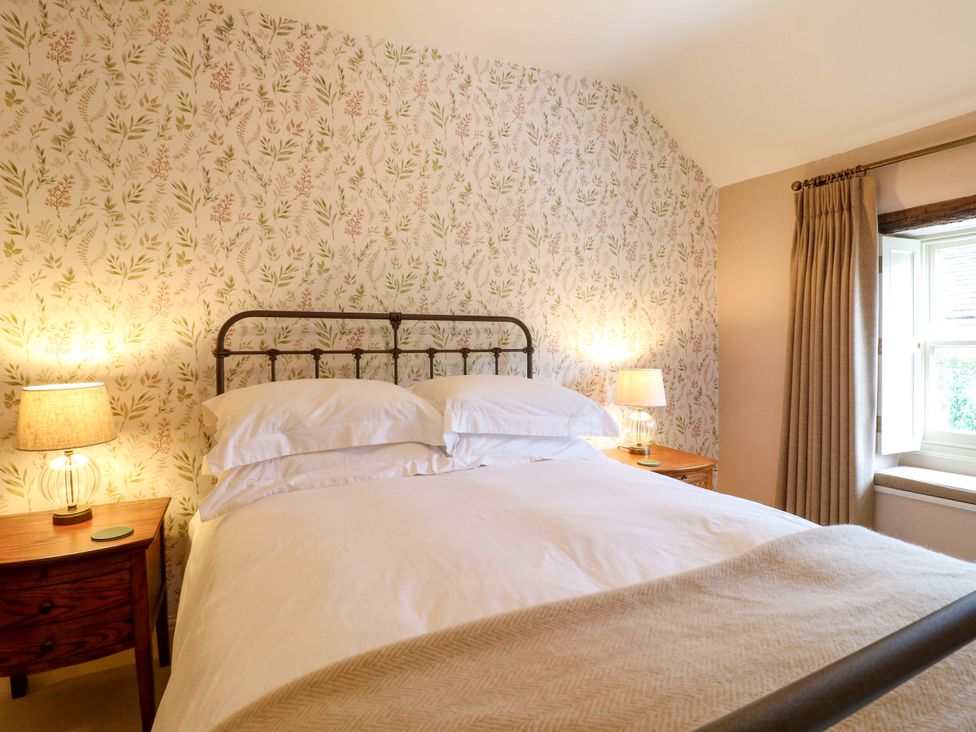 A bedroom with a bed, nightstands, lamps and curtains at Christmas Cottage in Bakewell