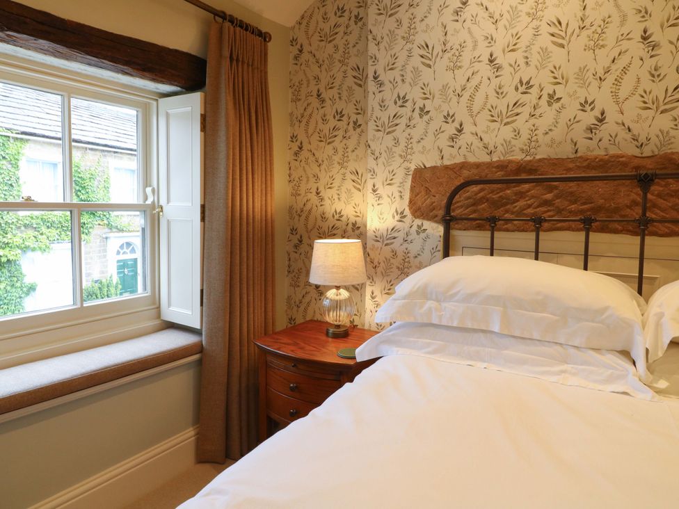 A bedroom with a window and lamp at Christmas Cottage in Bakewell