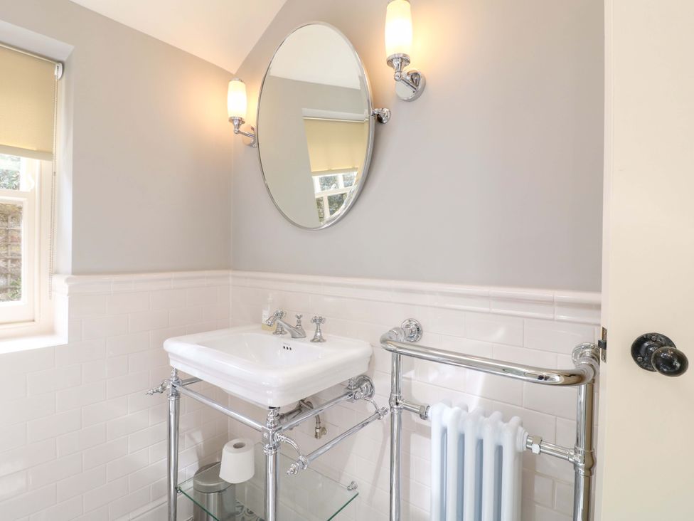 A bathroom with a sink, mirror, and radiator at Christmas Cottage in Bakewell