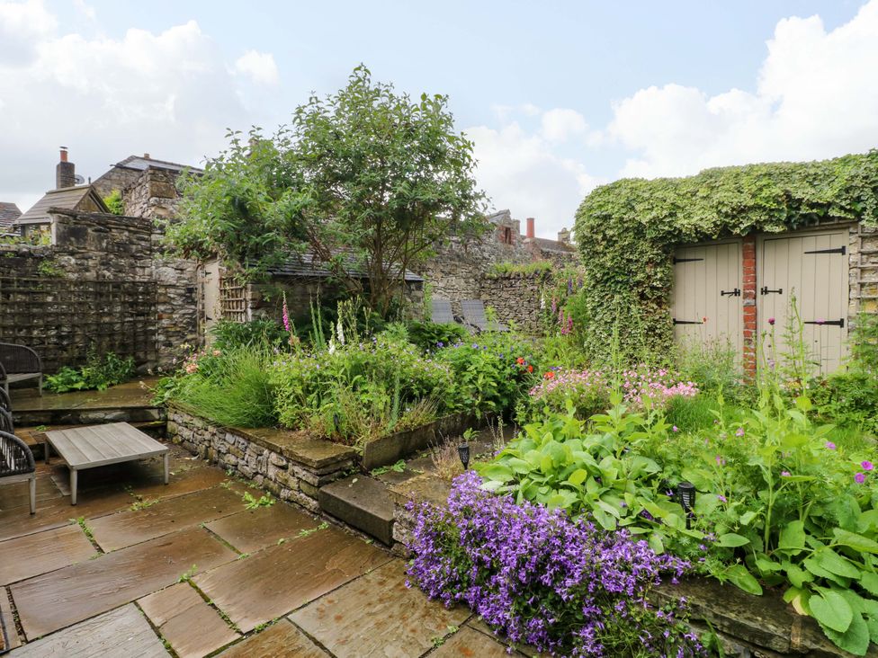 A garden with flowers and a wooden shed at Christmas Cottage in Bakewell