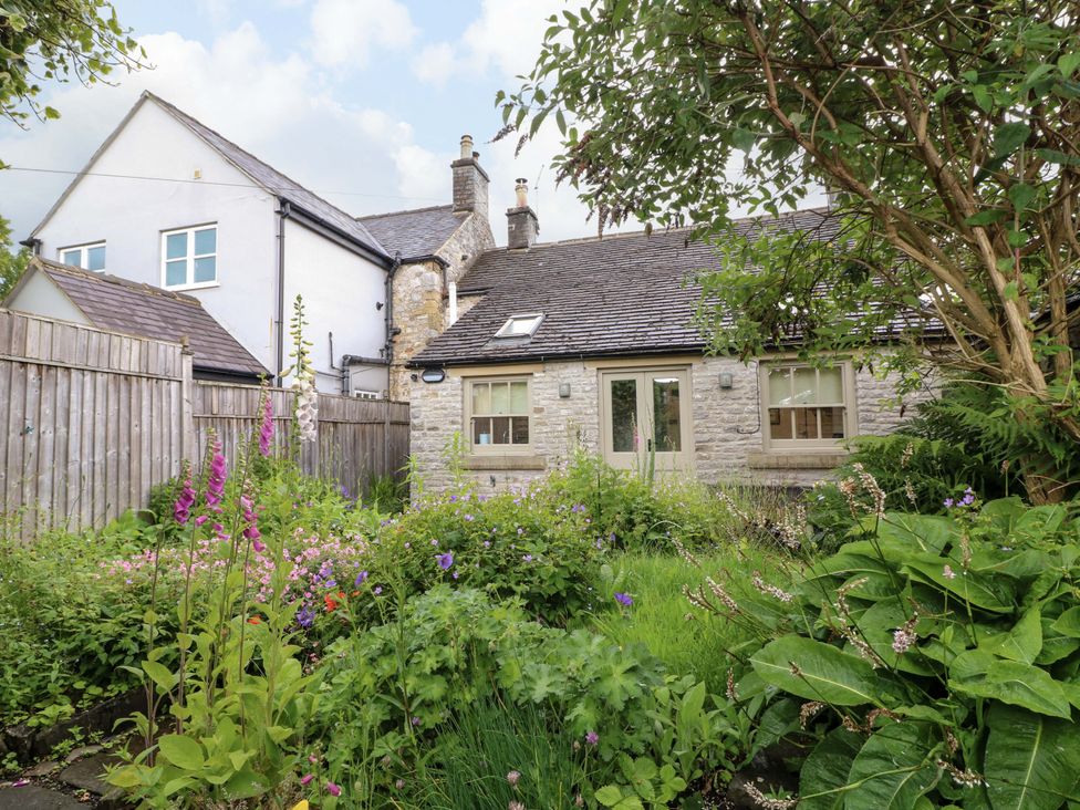 A garden with a stone house and flowers at Christmas Cottage in Bakewell