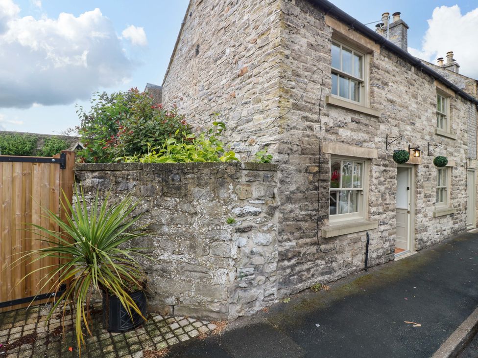 An outdoor view of a cottage with a stone wall, plants and a gate at Christmas Cottage in Bakewell