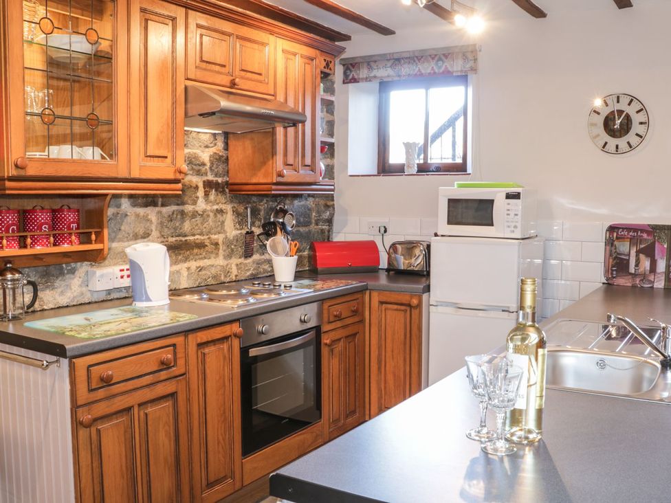 A kitchen with wooden cabinets and appliances at The Granary in Bucknell