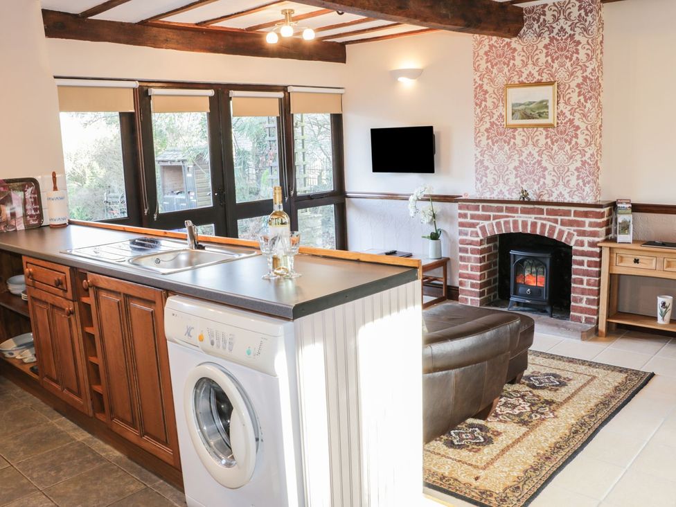A kitchen with a washing machine and a fireplace at The Granary in Bucknell