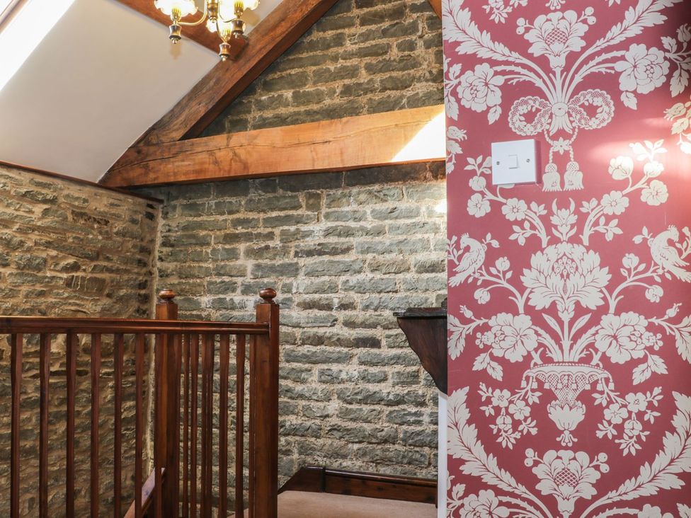 A hallway with a wooden railing and stone wall at The Granary in Bucknell