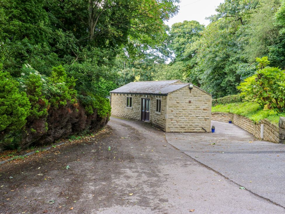A building near a driveway surrounded by trees and bushes at The Lodge in Brighouse