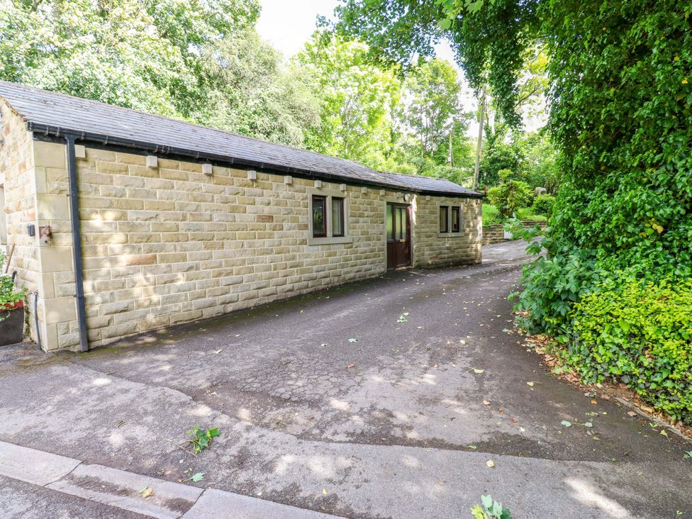 An exterior view of a stone building with windows and a pathway at The Lodge in Brighouse