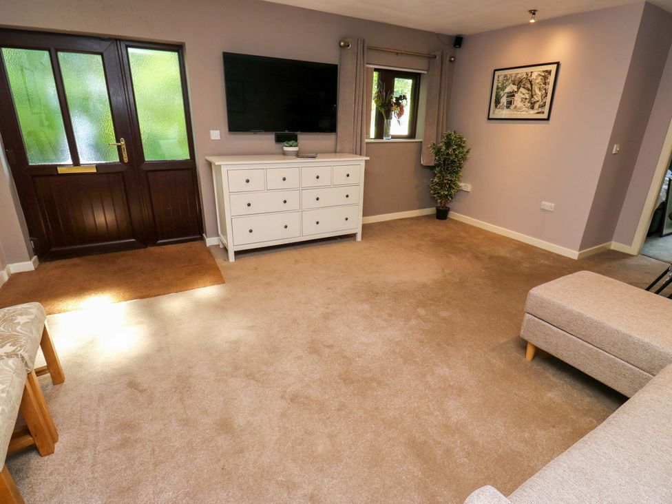 A living room with a television and drawers at The Lodge in Brighouse