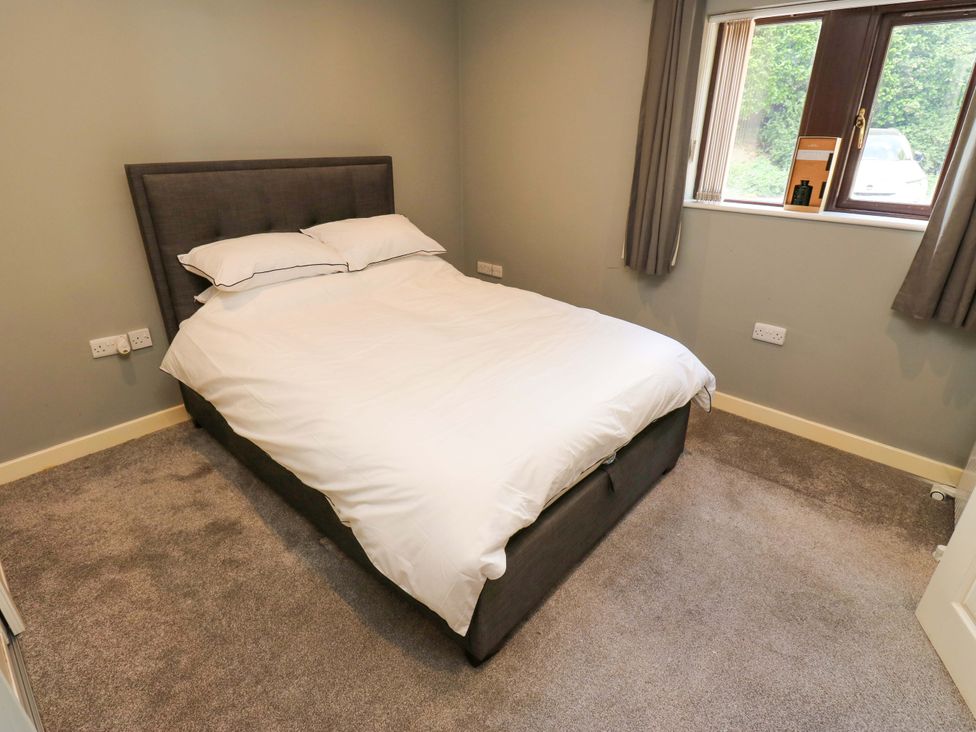 A bedroom with a bed and window at The Lodge in Brighouse