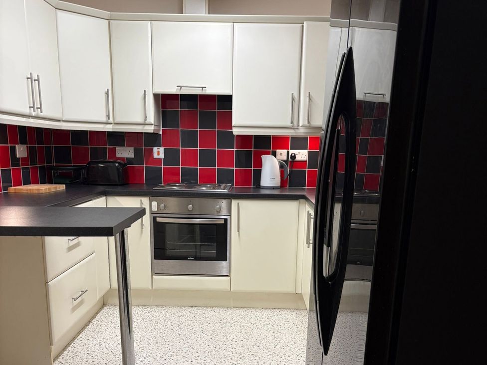 A kitchen with cabinets, oven, kettle, and toaster at The Lodge in Brighouse