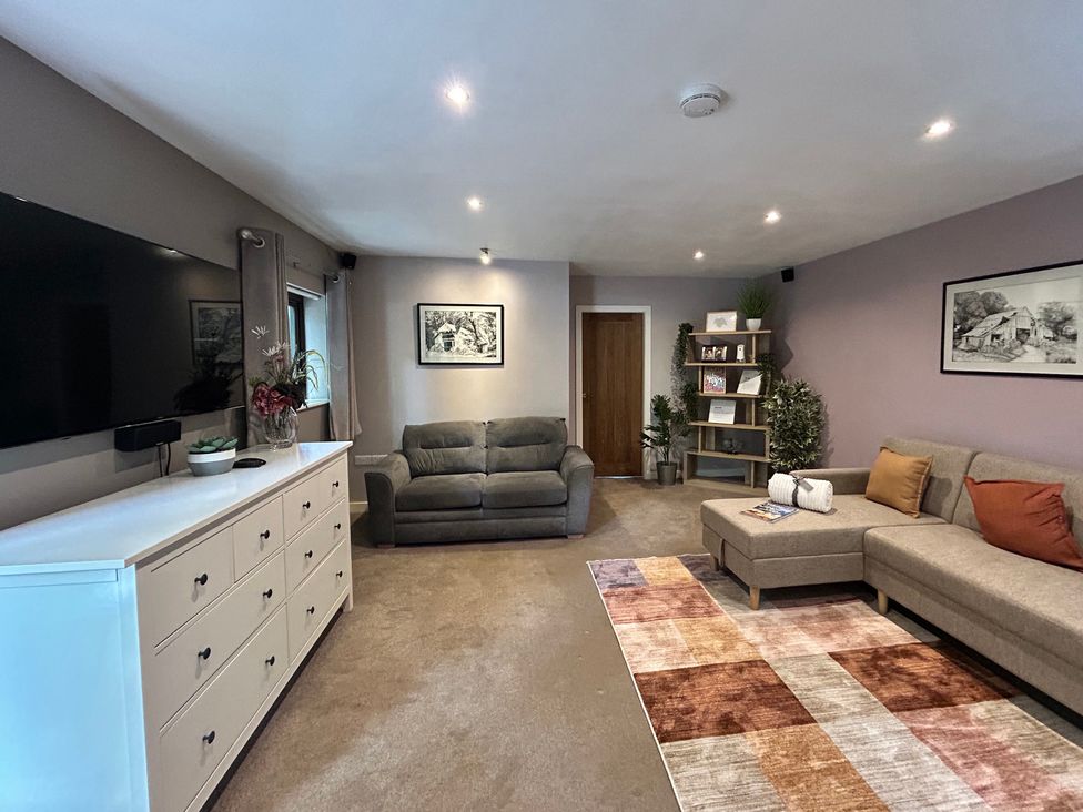 A living room with a sofa and television at The Lodge in Brighouse