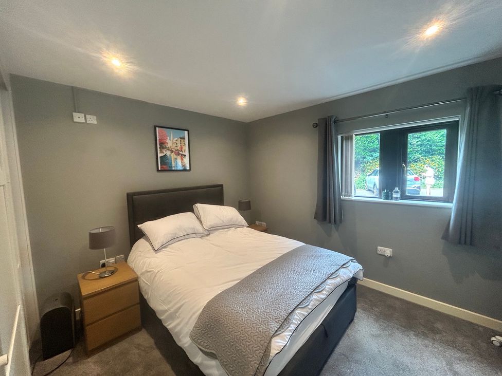 A bedroom with a bed and nightstand at The Lodge in Brighouse