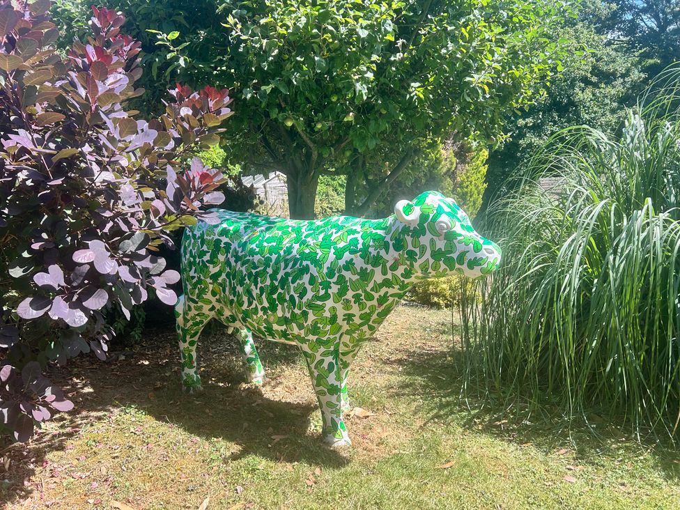 A decorative cow sculpture among plants in the garden at The Lodge in Brighouse