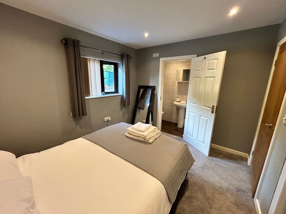 A bedroom with a bed and a washroom accessible through a door at The Lodge in Brighouse