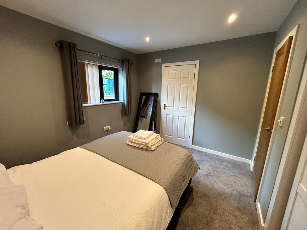 A bedroom with a bed and mirror at The Lodge in Brighouse