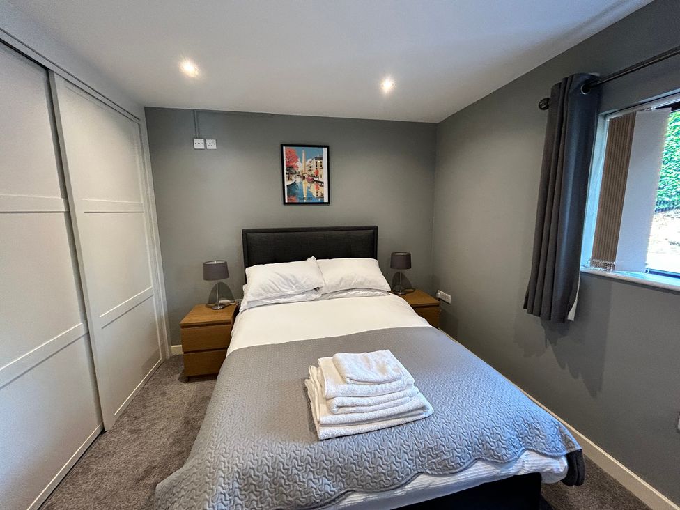 A bedroom with a bed and bedside tables at The Lodge in Brighouse