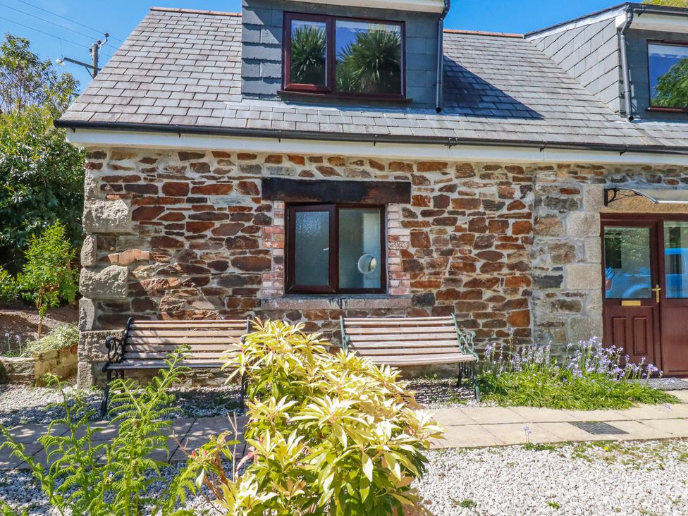 An exterior view of a property with a stone wall and bench at Camelia Cottage in St. Austell