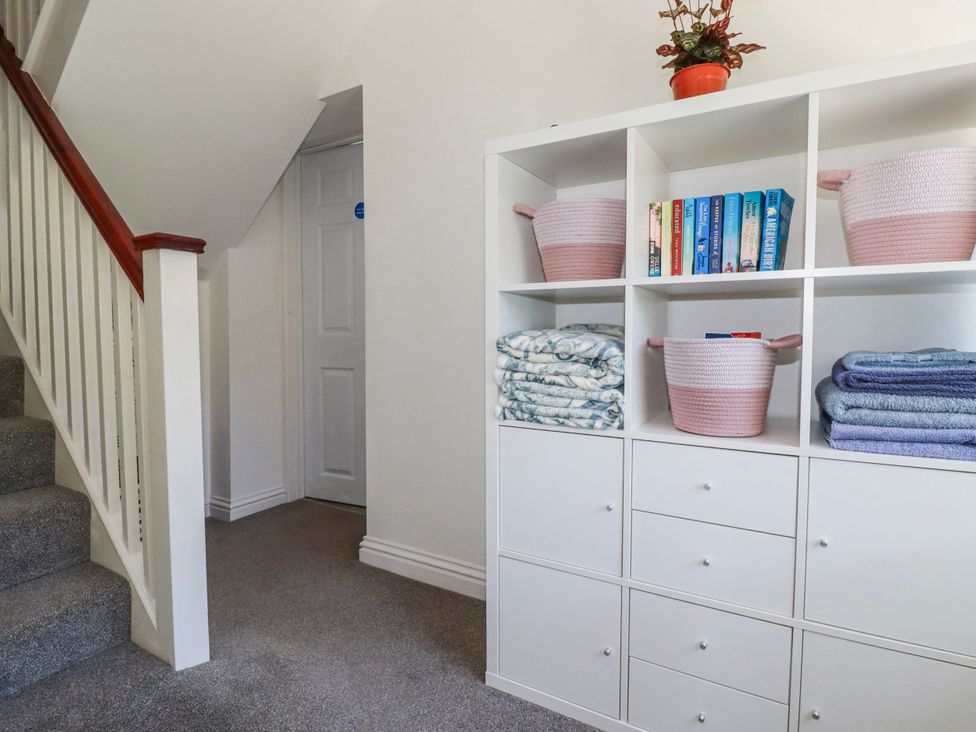 A hallway with a bookshelf and staircase at Camelia Cottage in St. Austell