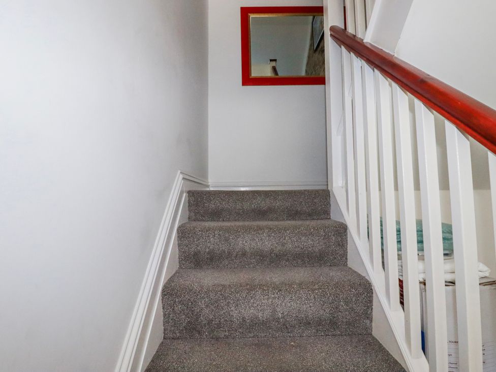 A staircase with a handrail and a mirror at Camelia Cottage in St. Austell