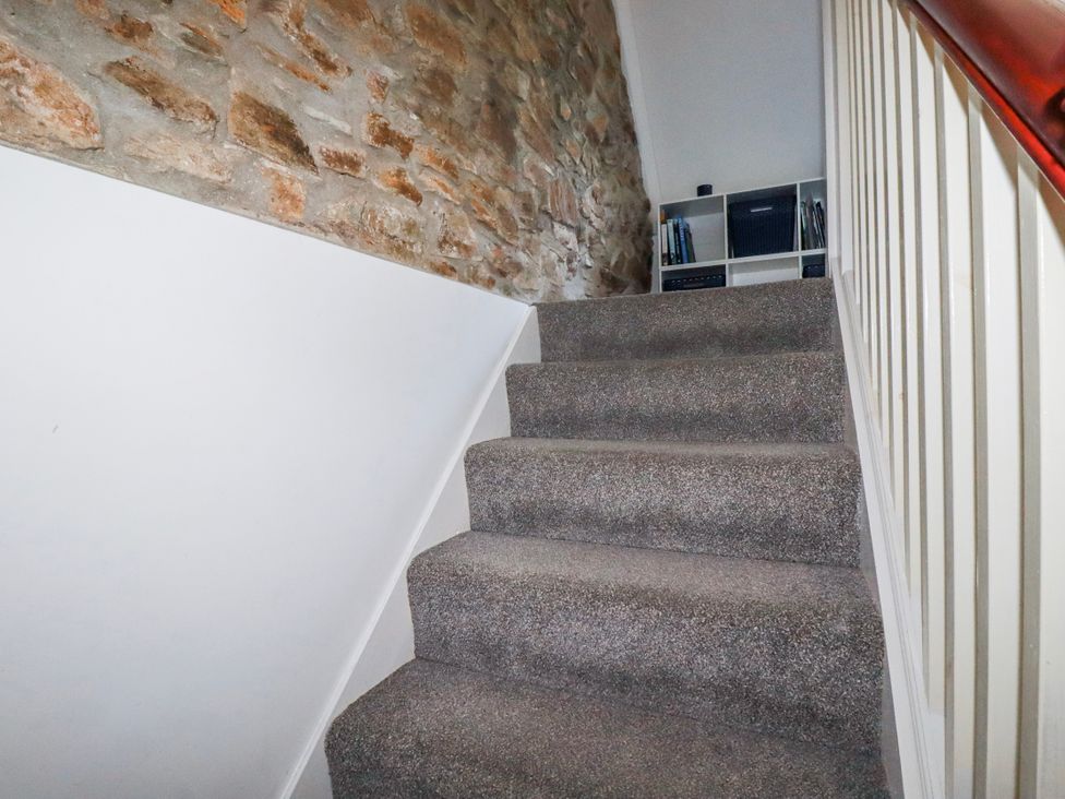 A staircase with a stone wall and shelf at Camelia Cottage St. Austell