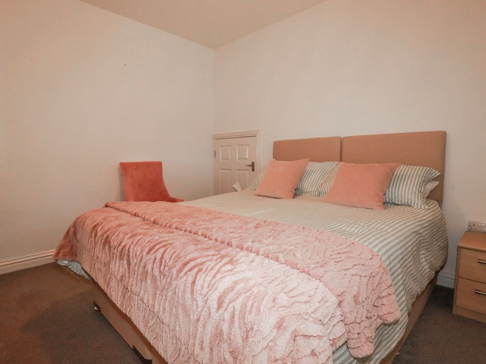 A bedroom with a large bed and a chair at Camelia Cottage in St. Austell