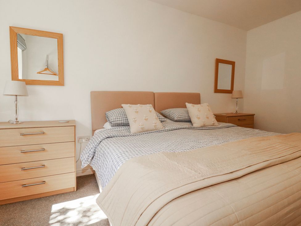 A bedroom with a bed and two mirrors at Camelia Cottage in St. Austell