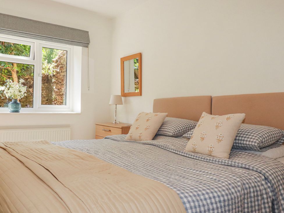 A bedroom with a bed and window at Camellia Cottage St. Austell