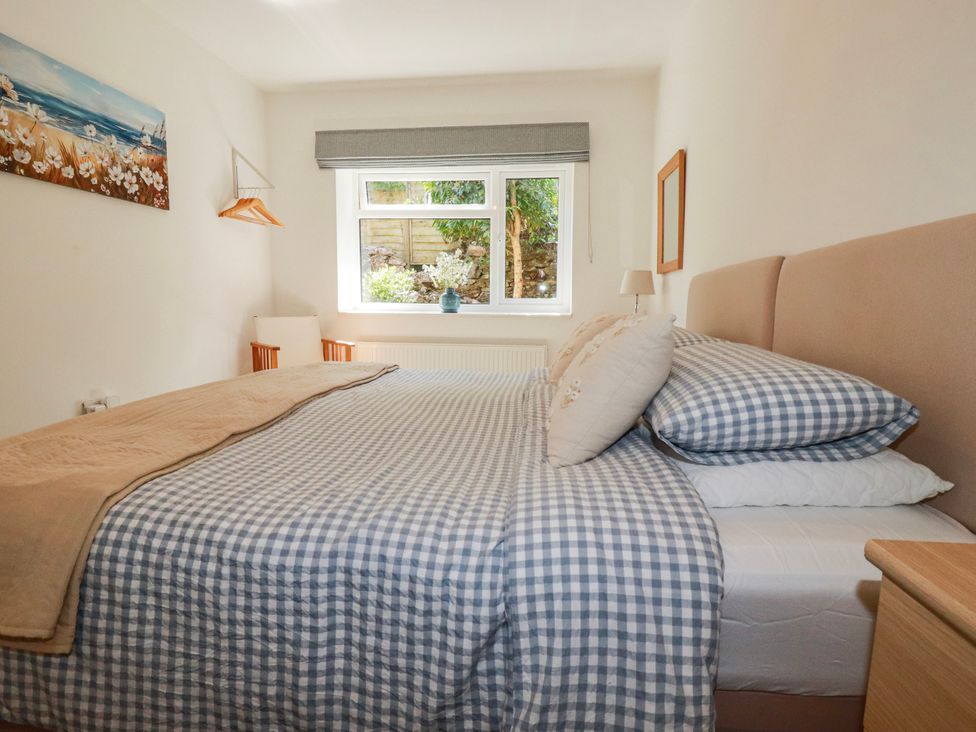 A bedroom with a bed and a window at Camelia Cottage in St. Austell