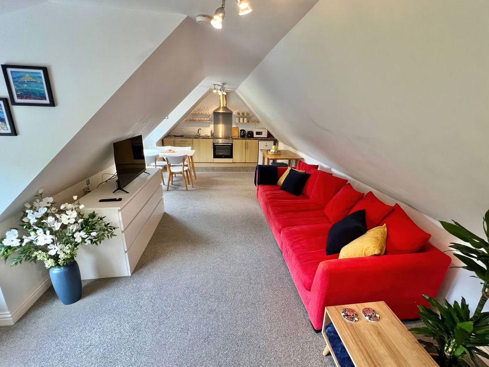 A living room with a sofa and dining table at Hydrangea Cottage Tregrehan Mills near St. Austell