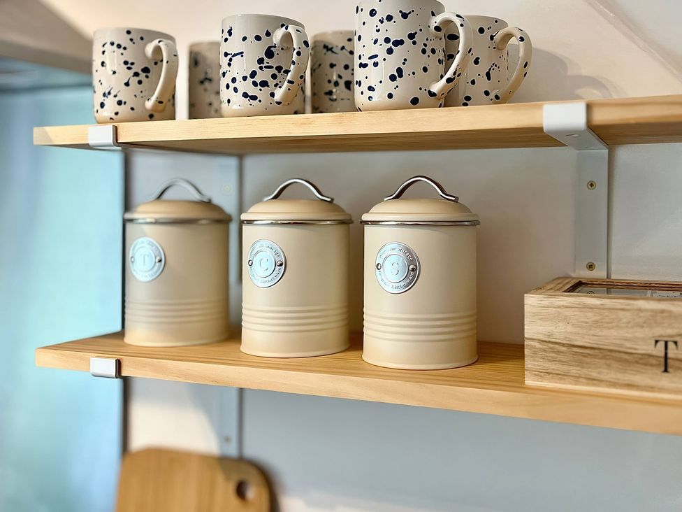 Kitchen shelves with mugs and canisters at Hydrangea Cottage Tregrehan Mills near St. Austell