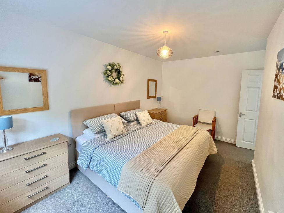 A bedroom with a bed and bedside furniture at Hydrangea Cottage, Tregrehan Mills near St. Austell