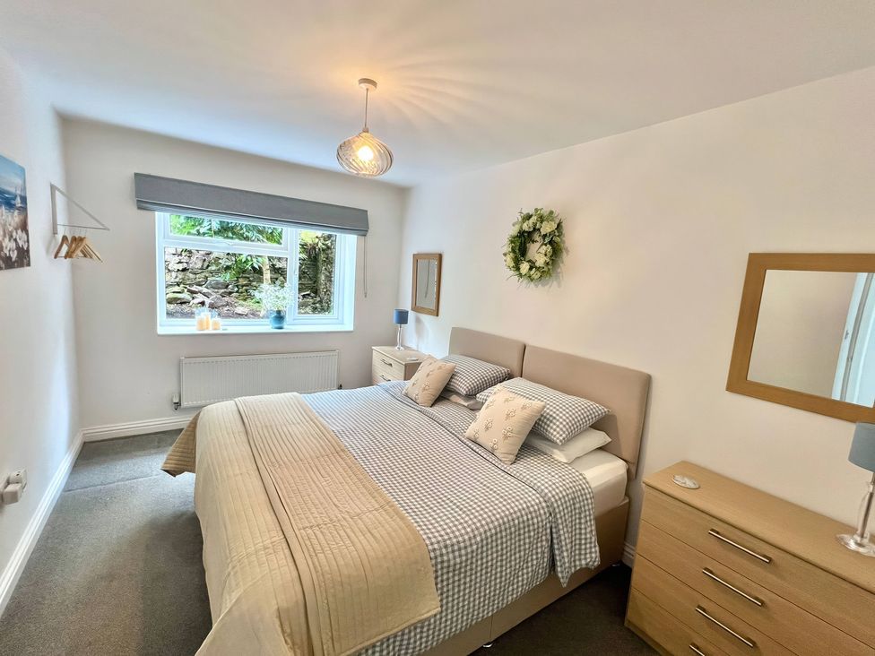 A bedroom with a bed and window at Hydrangea Cottage in Tregrehan Mills near St. Austell