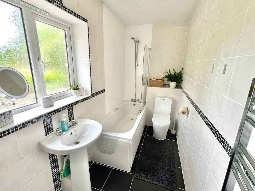 A bathroom featuring a bath, toilet, and sink at Hydrangea Cottage in Tregrehan Mills near St. Austell