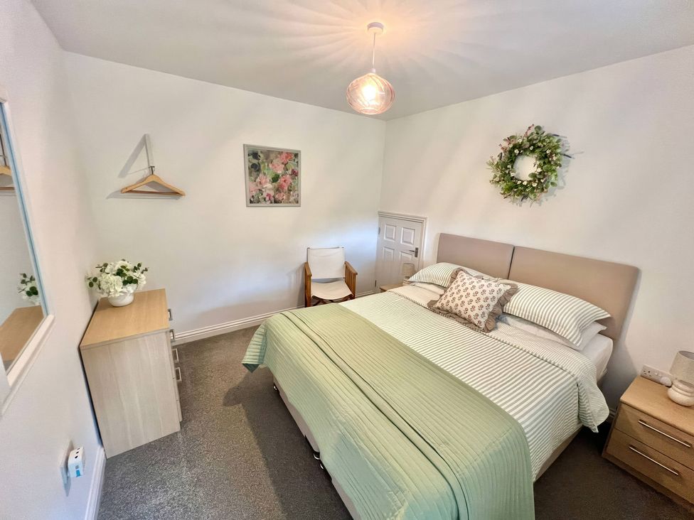 A bedroom with a bed and nightstand at Hydrangea Cottage in Tregrehan Mills near St. Austell
