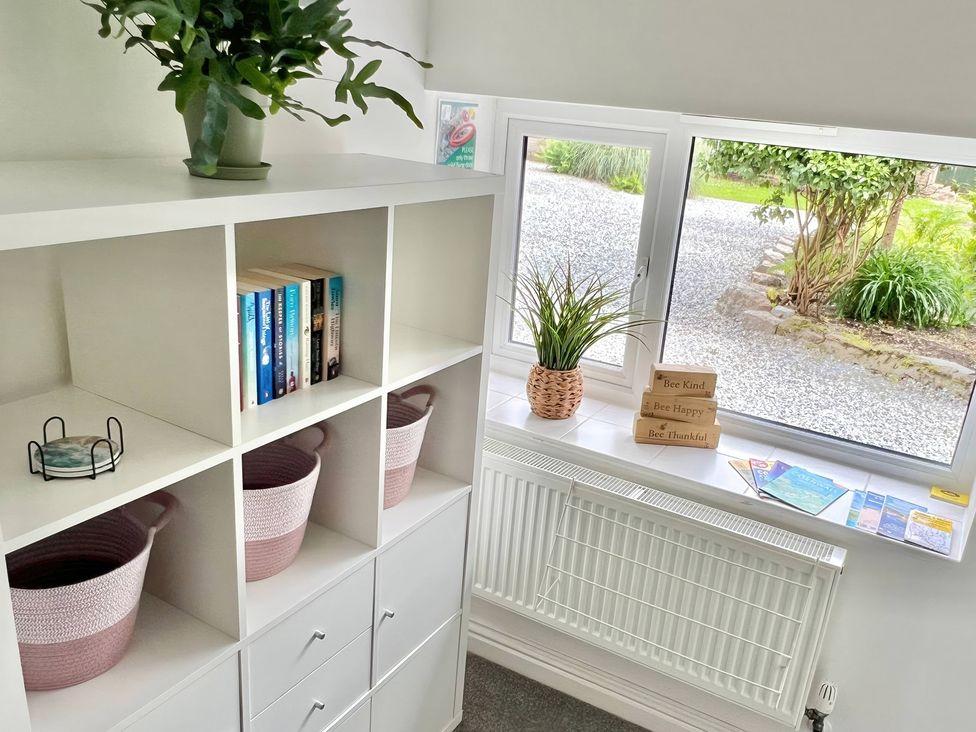 A shelf with books and plants at Hydrangea Cottage in Tregrehan Mills near St. Austell