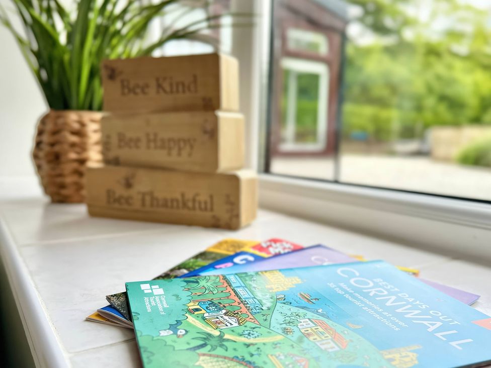 A wooden block decor and brochures on a windowsill at Hydrangea Cottage in Tregrehan Mills near St. Austell
