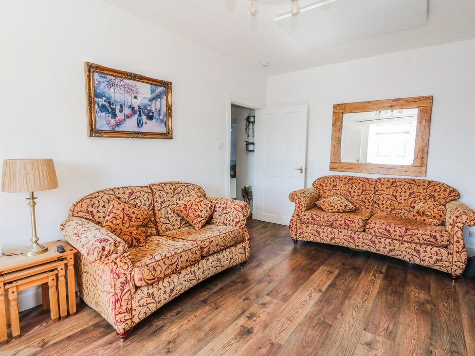 A living room with patterned sofas and a lamp at Schoolhouse in Oban