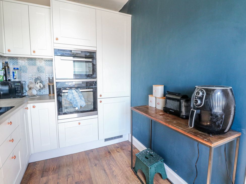 A kitchen with cabinets, oven, air fryer, and storage containers at Schoolhouse in Oban