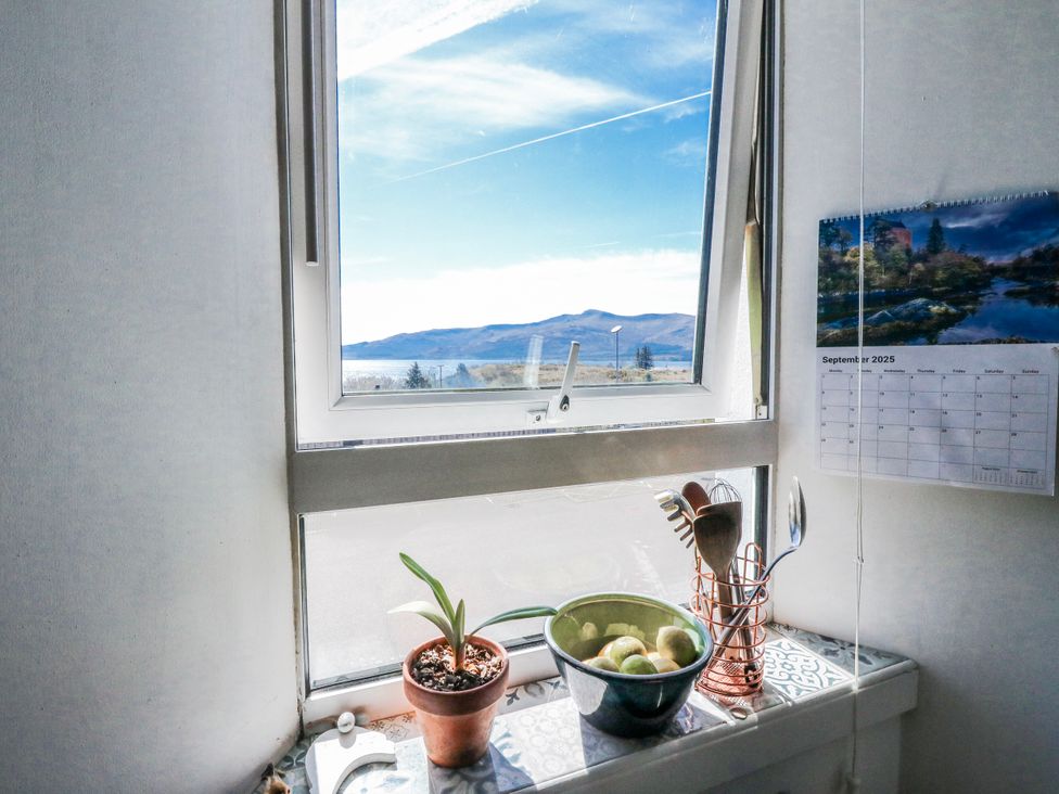 A kitchen window with a view and a bowl of apples at Schoolhouse in Oban