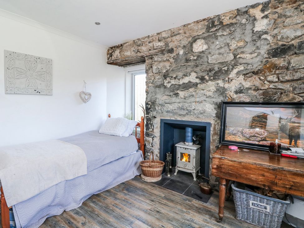 A bedroom with a bed and wood stove at Schoolhouse in Oban