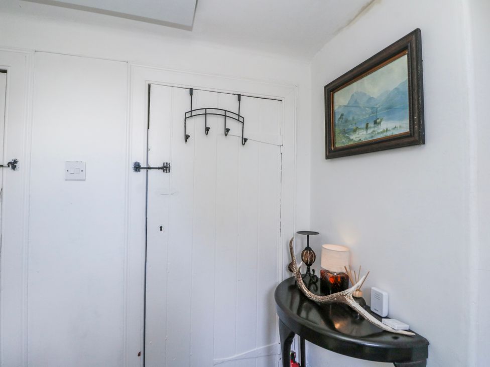 An entrance hall with a table, lamp and wall painting at Schoolhouse in Oban