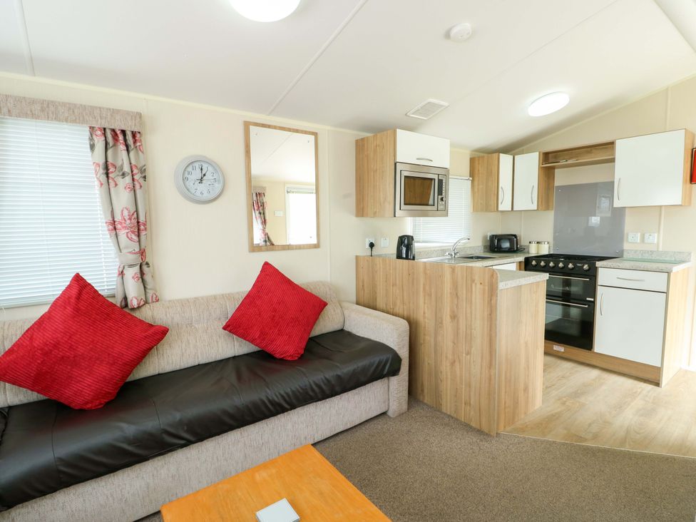 A living room with a sofa and kitchen units at W629 in Abergele